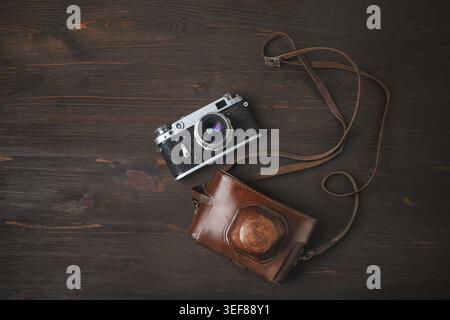 Fotocamera retrò e custodia su sfondo di legno. Posizione piatta Foto Stock