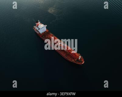 Vista aerea di una grande nave petroliera rossa che naviga nelle calme acque blu scuro del Mar Mediterraneo Augusta, Sicilia, Italia. Foto Stock