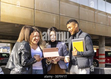 Ritratto di 4 uomini d'affari di etnia mista che lavorano insieme con un tablet per strada. Riunione di lavoro Foto Stock