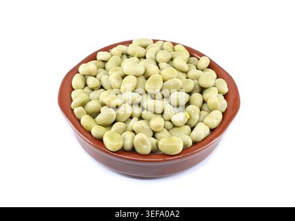 Fagioli larghi bolliti in una ciotola di argilla su sfondo bianco. Foto Stock