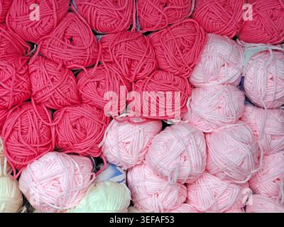 Primo piano di palle in filato multicolore impilate insieme, fibra morbida, materiale per maglieria, sfondo a cornice intera Foto Stock