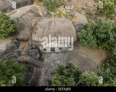 Vista aerea del Santuario de Nossa Senhora da Lapa, una cappella in pietra unica costruita sotto un massiccio masso circondato da alberi lussureggianti e terreno roccioso in S. Foto Stock