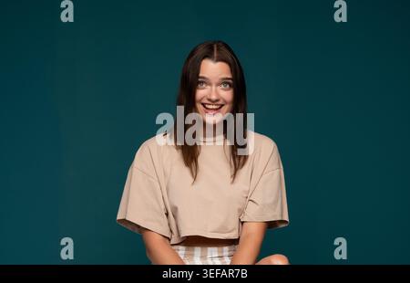 Giovane donna che si sente sorpreso e felice, sorridendo ampiamente con grandi occhi, esprimendo autentica gioia e meraviglia Foto Stock