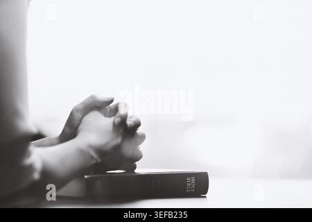 Il devoto tempo di preghiera di un cristiano, mettendo entrambe le mani sulla Bibbia e offrendo preghiere serene in silenzio. Foto Stock