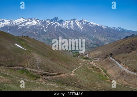 Montagne innevate e strade tortuose in un passo di montagna vicino a Bamiyan Afghanistan durante il tempo limpido Foto Stock