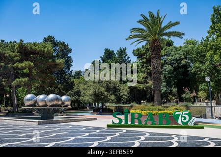 I visitatori apprezzano il verde e le attrazioni della piazza centrale di Baku, Azerbaigian, in una giornata di sole d'estate Foto Stock
