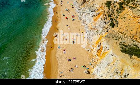 I visitatori possono godersi il sole e le attività sulla spiaggia di Tonel a Sagres, Algarve, Portogallo, con persone e ombrelloni sulla sabbia Foto Stock