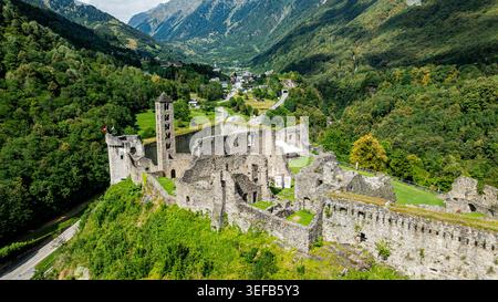 La vista aerea mostra le rovine del castello di Mesocco circondate da montagne e vegetazione in Svizzera Foto Stock