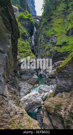 L'acqua scorre attraverso il canyon roccioso mentre il ponte si estende sopra in Svizzera durante le ore diurne Foto Stock