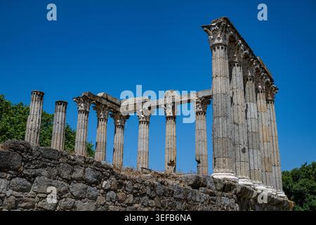 Esplora i resti del tempio romano di Evora in Portogallo, con antiche colonne e cielo blu Foto Stock