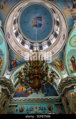 Vista interna della cattedrale di San Pietro e San Paolo con murales colorati e un grande lampadario a Gomel Foto Stock