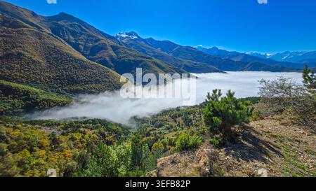 Paesaggio montano nell'Ossezia settentrionale con nebbia che copre la valle in una giornata di sole Foto Stock