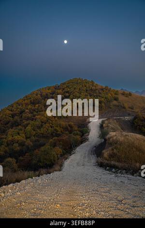 Strada che si snoda tra le montagne al chiaro di luna in Cecenia, regione del Caucaso della Russia Foto Stock