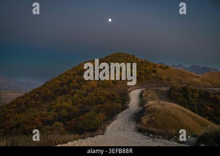 Strada che si snoda tra le montagne sotto il cielo notturno in Cecenia, regione del Caucaso della Russia Foto Stock