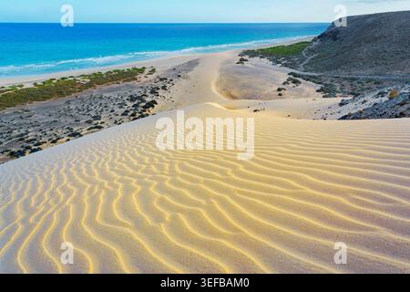 Onde e dune si incontrano sotto il cielo limpido alla spiaggia di Sotavento a Fuerteventura Foto Stock