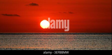 Tramonto sull'oceano a Mauritius, che mostra il sole che tramonta all'orizzonte mentre la giornata termina e la sera si avvicina con colori caldi Foto Stock