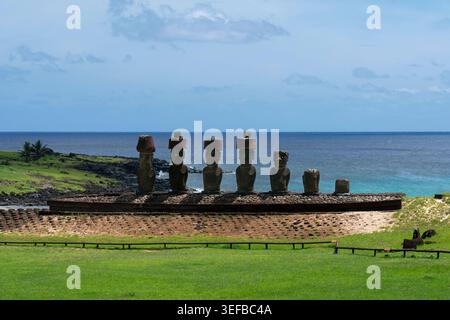 Le statue moai sorgono sulla spiaggia di Anakena con l'oceano sullo sfondo e la terra verde intorno a loro a Rapa Nui, Cile Foto Stock