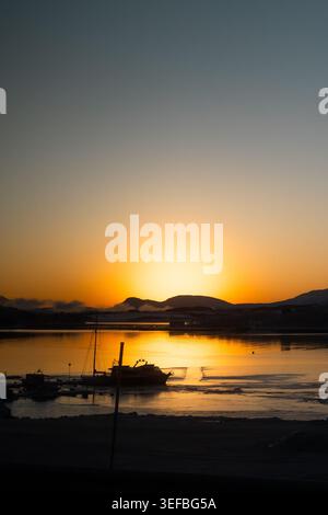 Brillante alba dorata sul porto con barche e montagne sagomate, il primo sole dopo la notte polare, soldagen, Tromsø, Norvegia artica. Foto Stock