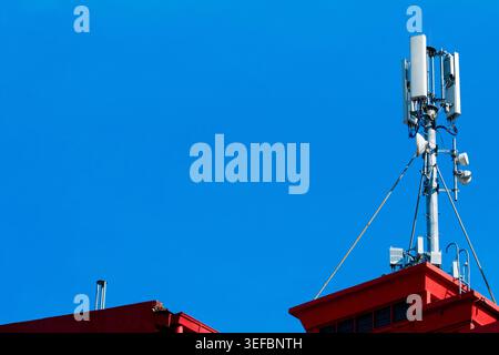 Un'antenna mobile montata su un tetto, che fornisce copertura di comunicazione wireless per l'area circostante in ambienti urbani. Foto Stock