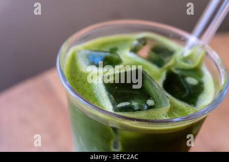 Il vetro trasparente contiene una vivace bevanda di matcha verde ghiacciata. I cubetti di gelatina di tè verde dolce galleggiano all'interno. La cannuccia trasparente fuoriesce dalla bevanda. Fresco e rif Foto Stock