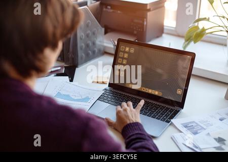 Donna di mezza età che utilizza un notebook per l'analisi dei dati aziendali Foto Stock