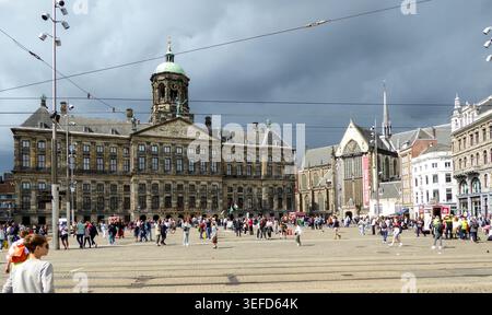 Piazza urbana trafficata con edifici storici sotto un cielo buio ad Amsterdam, che mostra un'atmosfera vivace della città. Foto Stock