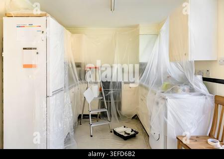 Cucina protetta con lenzuola in plastica e parapolvere prima di lavori di verniciatura e decorazione del soffitto Foto Stock