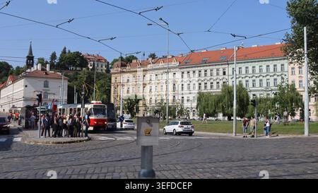 Tradizionale tram rosso e bianco che passa lungo il lungofiume e le affascinanti stradine acciottolate della storica Praga, Repubblica Ceca. Foto Stock