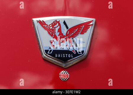 Un raro badge Arnolt Bristol degli anni '1950 montato su un cofano rosso ondulato con un piccolo badge auto 1000 miglia con sfondo a scacchi. Foto Stock