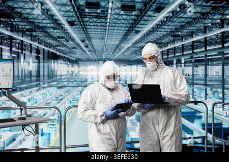 Progettazione del layout dei microchip, programma EDA e team di tecnici nell'impianto di produzione Industry 4,0. Revisione di schemi di fabbrica intelligenti, apparecchiature per semiconduttori automatizzate e brainstorming dei colleghi Foto Stock