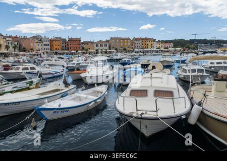 Piccoli motoscafi e imbarcazioni da diporto ormeggiati nel pittoresco porto di Rovigno con colorati edifici costieri sullo sfondo, Istria, Croazia Foto Stock
