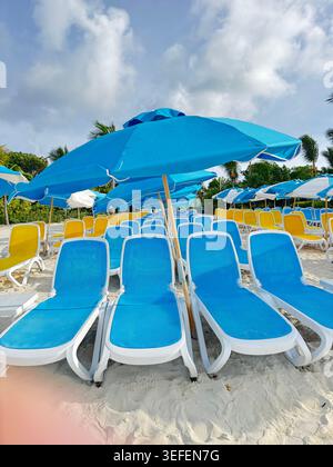 Lunghe file di sedie a sdraio vuote blu e bianche sotto ombrelloni blu su una spiaggia del resort Foto Stock