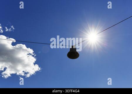 Campana singola scartata appesa su cavo d'acciaio, orchestra, scultura sonora Untuned Bell, artista norvegese A K Dolven, raggi del sole, cumulus in estate, vista Foto Stock