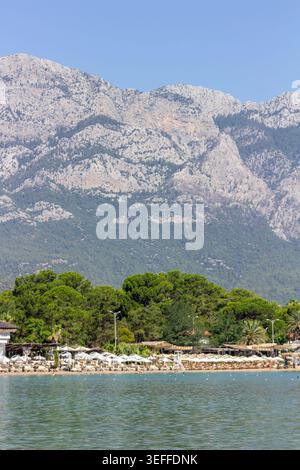 Spiaggia al chiaro di luna a Kemer, Türkiye, con costa mediterranea, costa boscosa e montagne del Tauro che si innalzano sopra l'area del resort Foto Stock