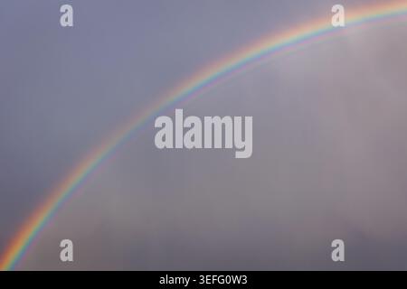 Un doppio arcobaleno vibrante che appare in un cielo buio e tempestoso dopo la pioggia Foto Stock