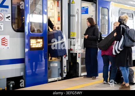 Varsavia, Polonia - 13 aprile 2026: I viaggiatori con valigie e borse si preparano a salire a bordo di un treno alla banchina della stazione, catturando l'esperienza di tutti i giorni Foto Stock
