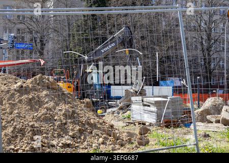 Varsavia, Polonia - 13 aprile 2026: Escavatore Volvo parcheggiato in un cantiere urbano con mucchi di terreno e materiali da costruzione, riflettendo la professione Foto Stock