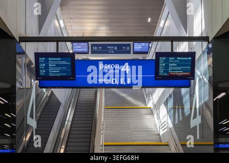 Varsavia, Polonia - 13 aprile 2026: Espositori informativi e scale mobili in una stazione ferroviaria contemporanea con segnaletica per la navigazione e il trav Foto Stock