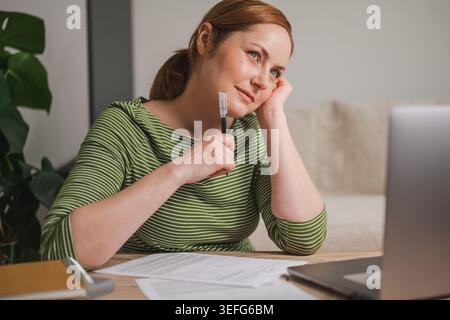 Donna che progetta finanze e pensiero mentre lavora da casa Foto Stock