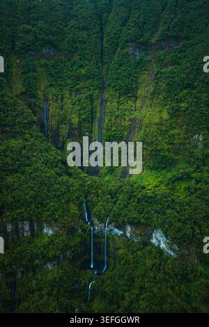 Vista aerea delle maestose cascate che scendono lungo le lussureggianti scogliere tropicali verdi, la Reunion, Francia. Foto Stock