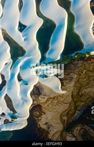 Vista aerea delle dune di sabbia bianca e delle lagune turchesi del Parque Nacional dos Lencois Maranhenses con un fiume tortuoso e una vegetazione verde a Lenc Foto Stock