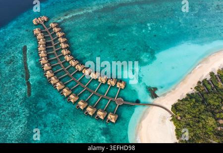 Vista aerea dei lussuosi bungalow sull'acqua disposti lungo un molo di legno in una laguna turchese con una spiaggia di sabbia bianca Hoarafushi, l'atollo Haa Alif, MALDI Foto Stock