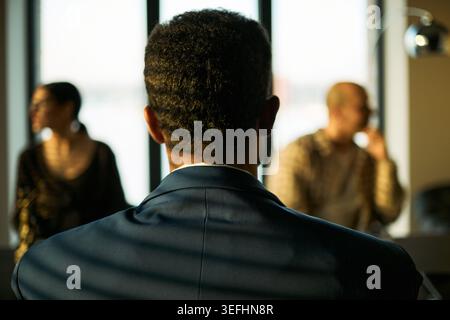 Vista posteriore dell'uomo di mezza età seduto tra una coppia separata durante la mediazione del divorzio, discutendo la risoluzione dei conflitti e il supporto legale. Ideale per il diritto di famiglia e la consulenza al marketing Foto Stock