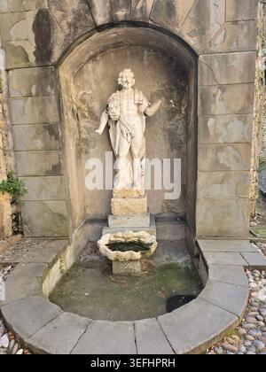Una fontana in pietra intemprata con una figura classica in una nicchia ad arco nelle strade storiche di Bergamo alta, Lombardia, Italia Foto Stock