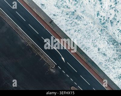 Vista aerea dall'alto verso il basso della Coastal Road e delle onde oceaniche che si infrangono Foto Stock