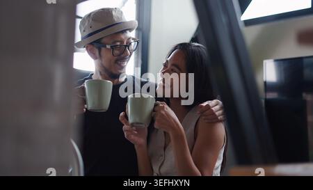 Felice giovane coppia variegata che si unisce al caffè a casa Foto Stock