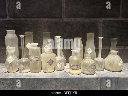 Bottiglie vintage per chimica da laboratorio e vetreria per chimica antica ricoperta di polvere. Vecchi contenitori di farmacia esposti su uno scaffale rustico. Foto Stock