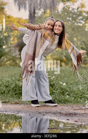 Mamma e figlia si godranno un gioioso momento autunnale, una posa giocosa e una calda luce naturale che creano una potente scena di vita familiare ideale per l'amore, bo Foto Stock