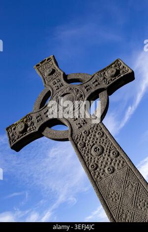 Vista delle intricate incisioni su una storica croce celtica in pietra presso l'Abbazia di Iona sotto un cielo azzurro. Isola di Iona, Scozia, Regno Unito. Foto Stock