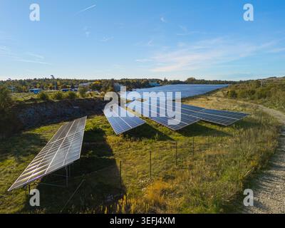 Vista aerea di una fattoria a energia solare con file di pannelli fotovoltaici in un'area rurale. Foto Stock